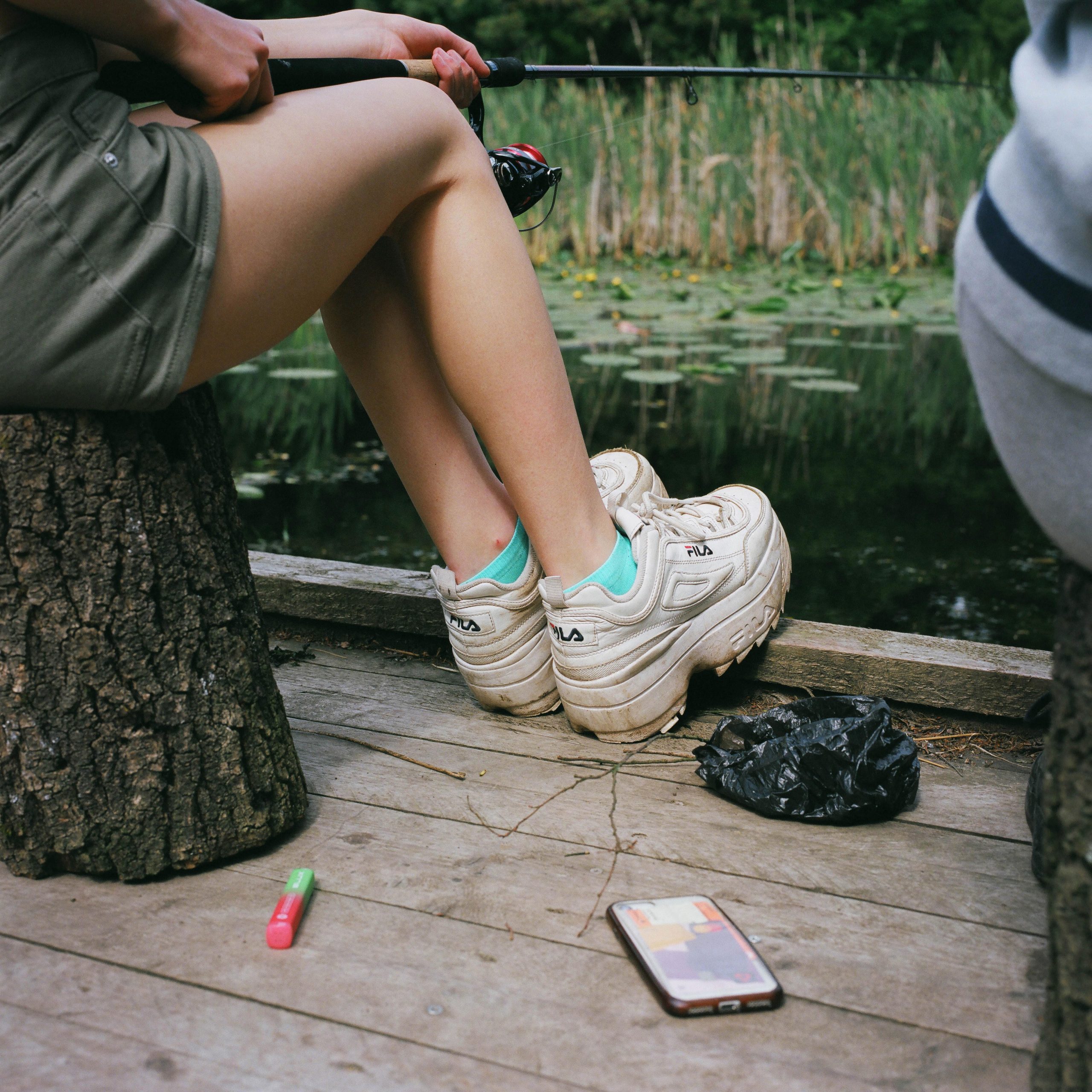 Photograph of a girl's legs and trainers as she sits fishing